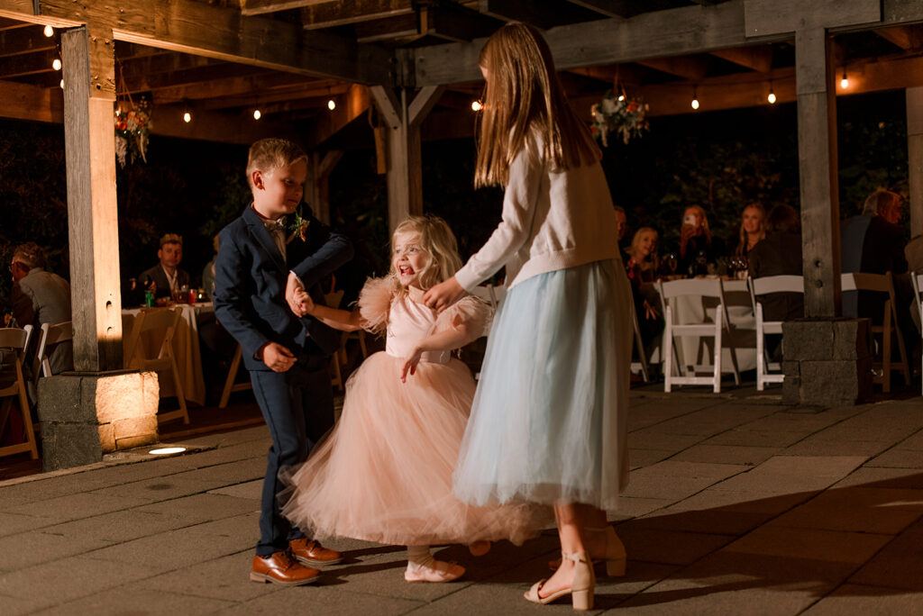 Kids at a wedding dance wildly on the dance floor while guests watch on