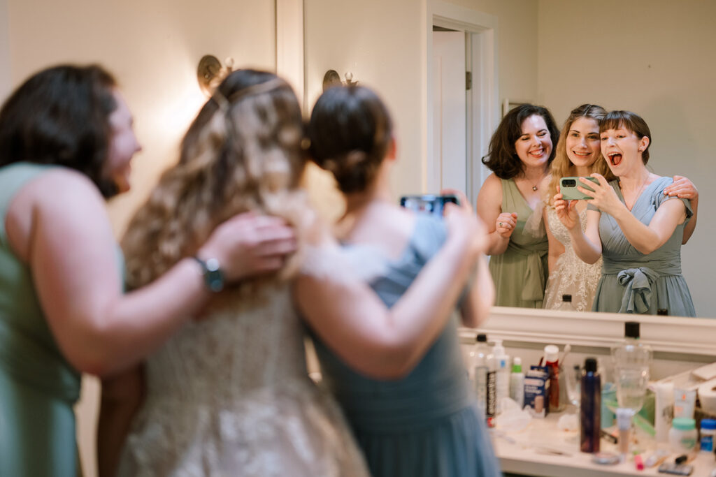 Documentary photography photo of bride and two bridesmaids take a selfie in the mirror while getting ready