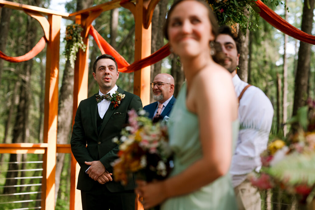 Documentary photography moment of groom standing at the alter and taking a deep breath as his brides walks down the aisle.
