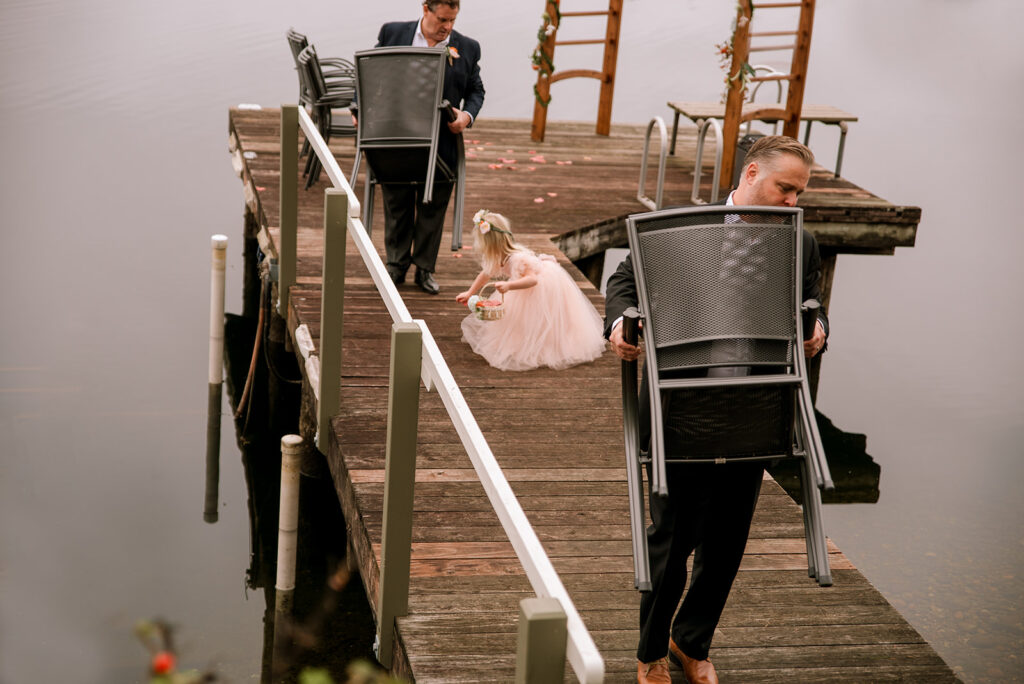 Documentary wedding moment where flower girl cleans up petals while the men put away chairs