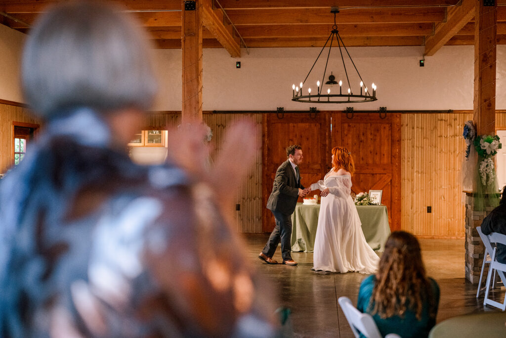 Documentary photography moment of couple doing their first dance and mom clapping for them