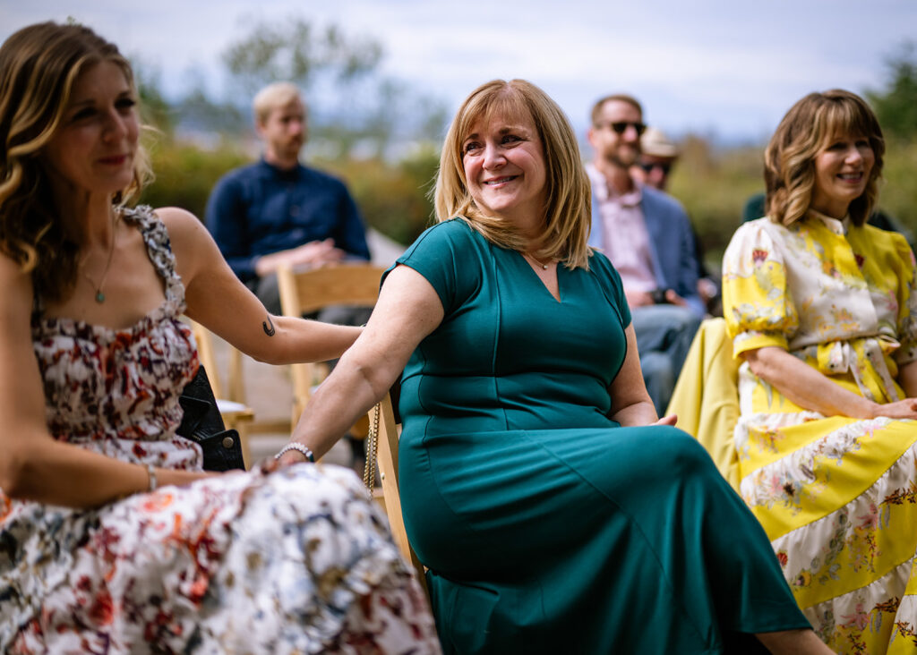 Mom tears up during daughters ceremony and looks over and smiles at the woman sitting next to her.