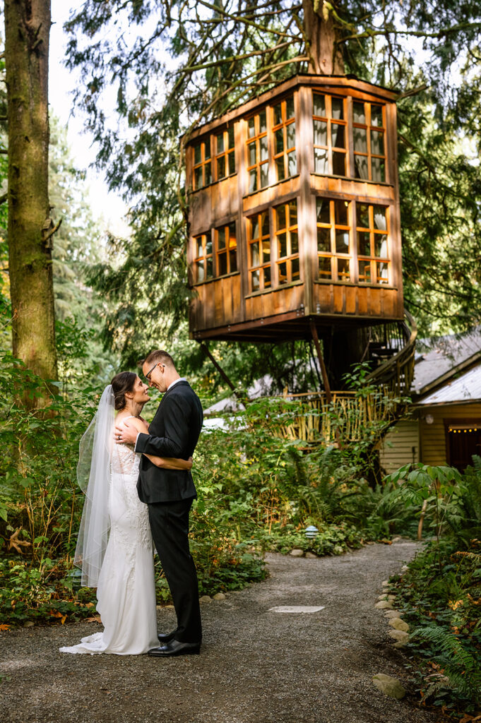 Couple stands under a tree house at Treehouse Point on their wedding day