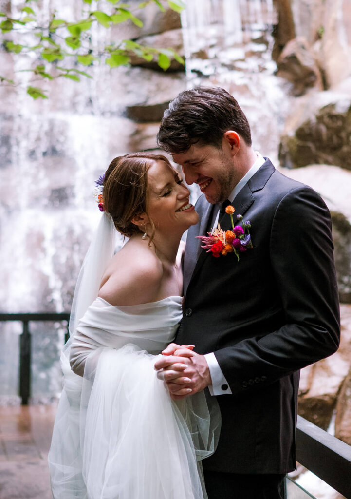 Bride and groom dance and laugh in front of waterfall in pioneer square seattle