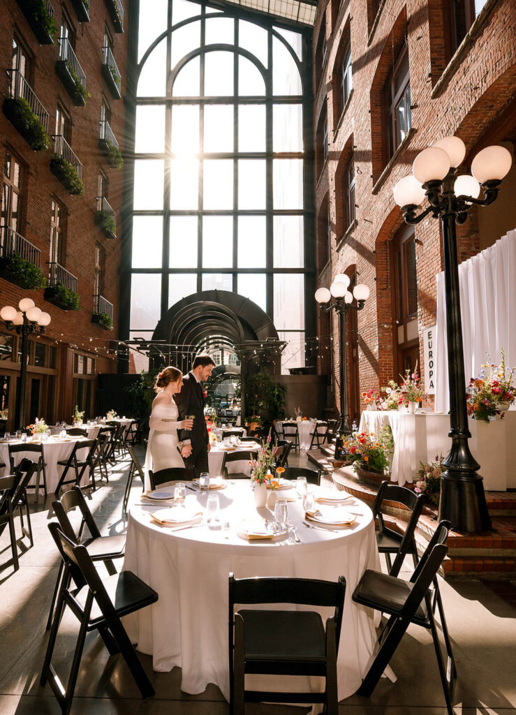 couple walks through reception atrium alone during europa seattle wedding